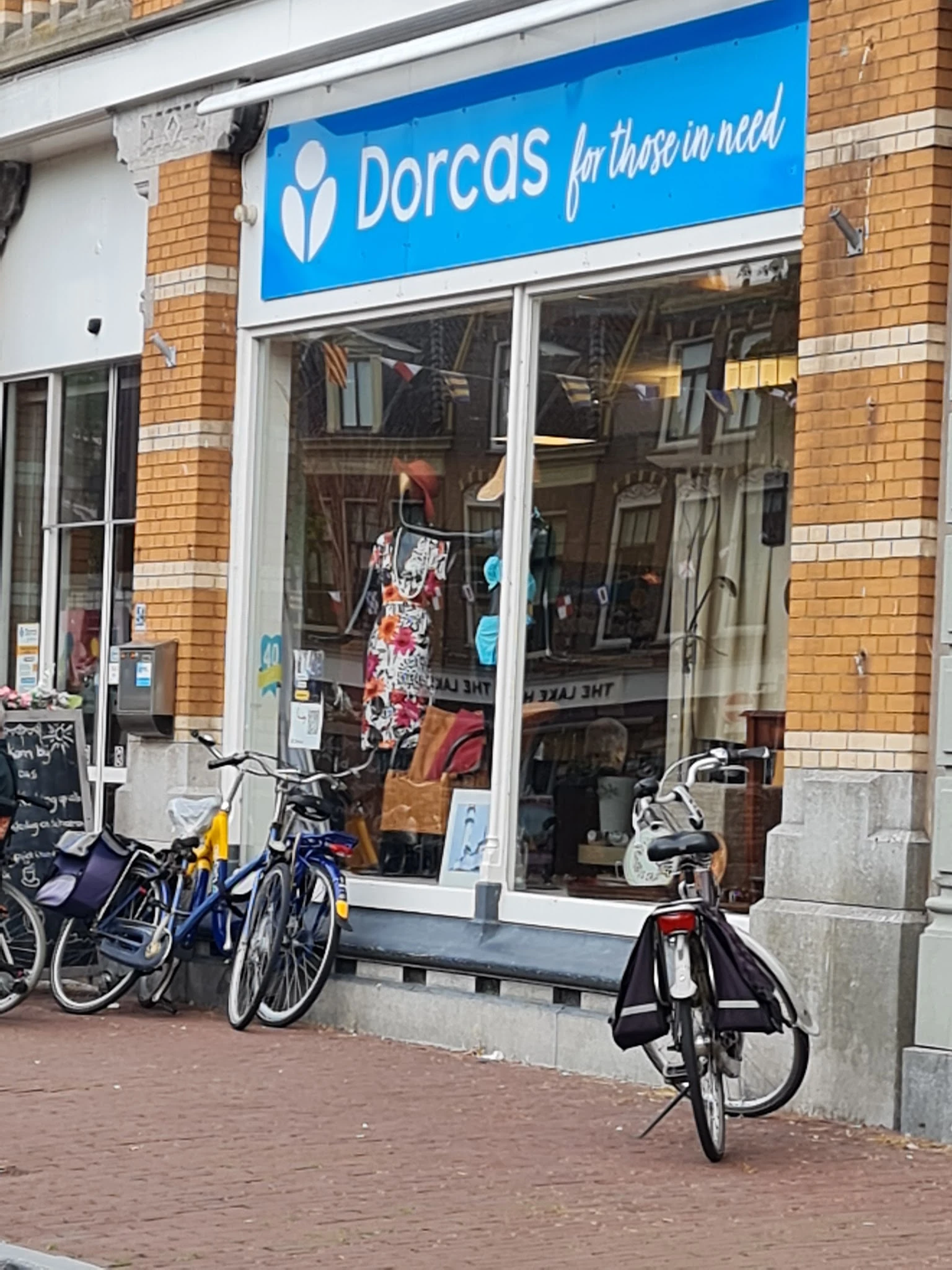 Winkelraam van kringloopwinkel met kleding en fietsen geparkeerd ervoor
