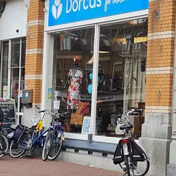 Winkelraam van kringloopwinkel met kleding en fietsen geparkeerd ervoor