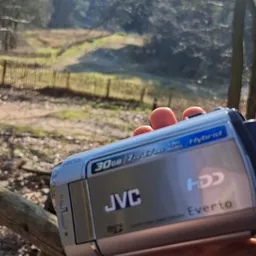 JVC videocamera met rode details tegen landelijk achtergrond