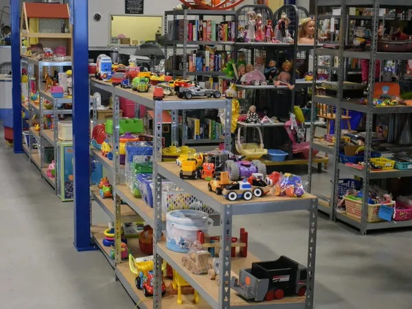 Winkelvloer met grijze stellingen vol speelgoed, poppen, boeken en diverse artikelen in een kringloopwinkel