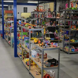 Overzicht van kringloopwinkel met stellingen vol speelgoed, boeken en diverse spullen
