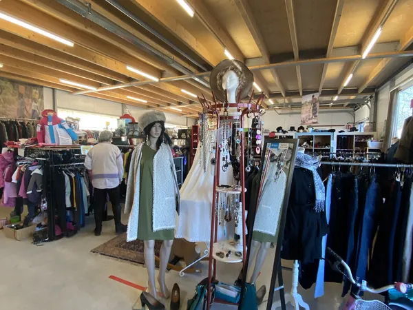 Winkelvloer met kledingrekken, etalagepoppen en hangers in een kringloopwinkel