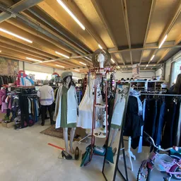 Winkelvloer met kledingrekken, etalagepoppen en hangers in een kringloopwinkel