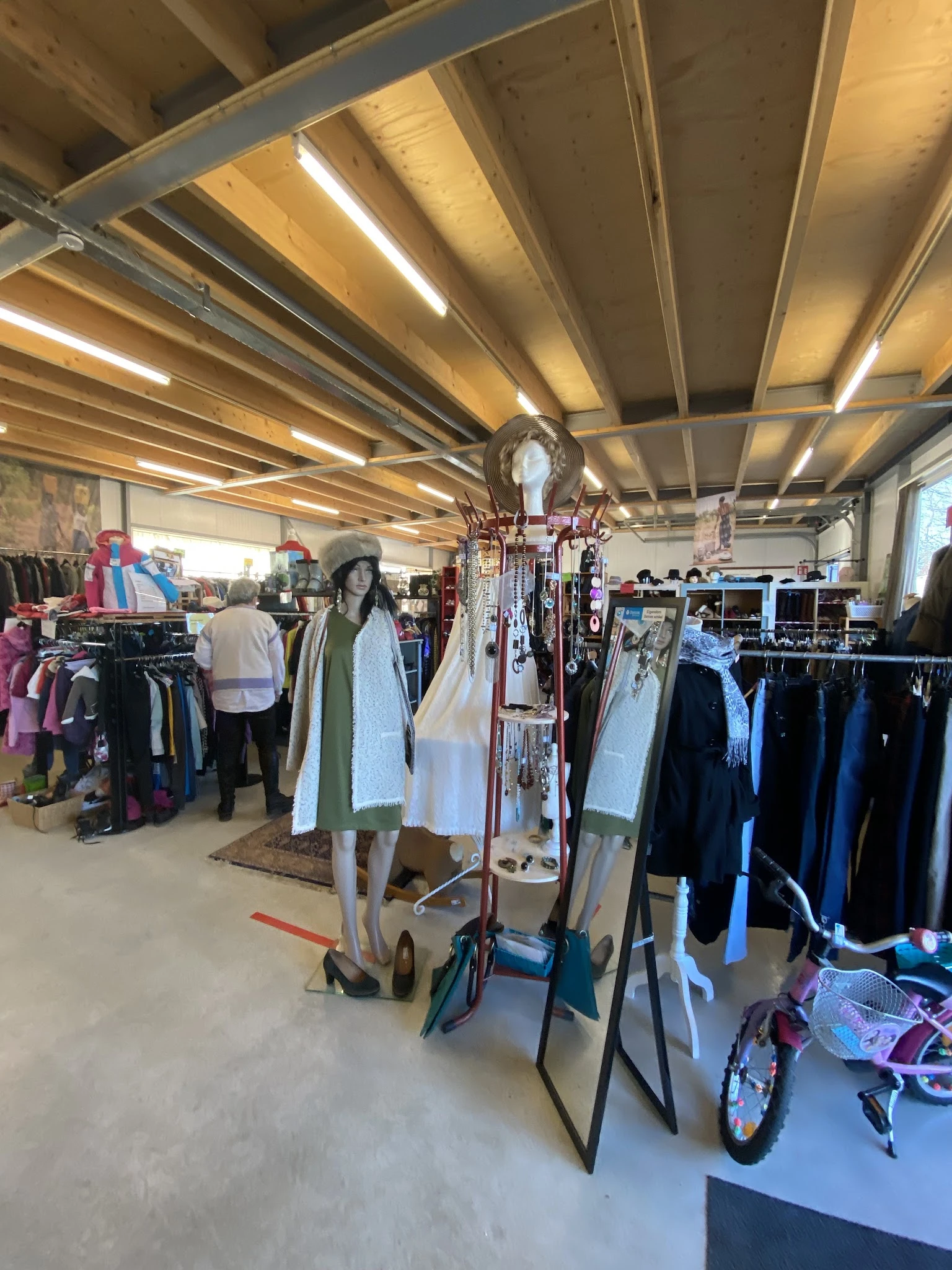 Winkelvloer met kledingrekken, etalagepoppen en tweedehands kleding onder LED-verlichting