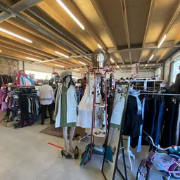 Winkelvloer met kledingrekken, etalagepoppen en tweedehands kleding onder LED-verlichting