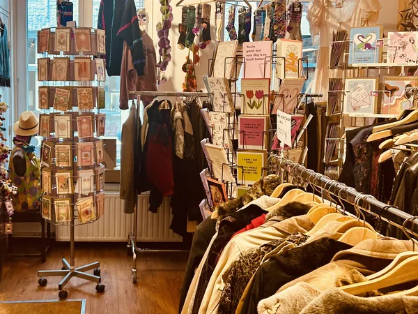 Vintage winkelinterieur met kledingrekken, uitgestalde kleding en een draaiend displayrek met kaarten