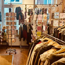 Vintage winkelinterieur met kledingrekken, uitgestalde kleding en een draaiend displayrek met kaarten