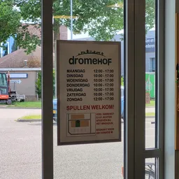 Openingstijdenbord van kringloopwinkel met logo, weekschema en welkomstbericht