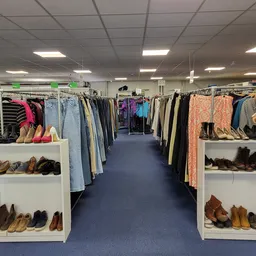 Winkelinterieur met kledingrekken en vitrines met schoenen op blauwe vloer