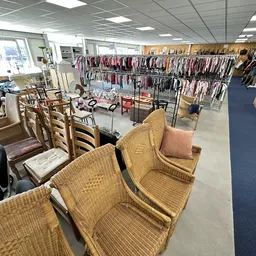 Winkelinterieur met rieten stoelen op de voorgrond en rekken met kleding op de achtergrond