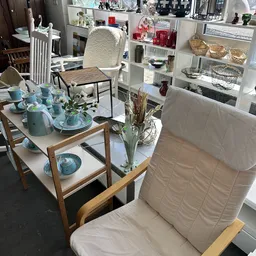 Uitgestalde tafelservies en keukengerei in de kringloopwinkel met turquoise borden, glazen, kannen en bloemen in een vaas