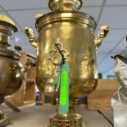 Close-up van een gouden samovar met groene kraan en decoratieve handvatten