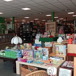 Binnenaanzicht van kringloopwinkel met speelgoed, boeken en diverse artikelen op tafels en stellingen
