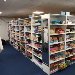 Kringloopwinkel met hoogstaande stellingen vol gevarieerde artikelen op blauwe vloer