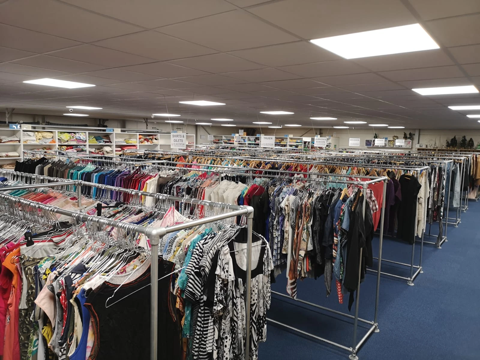 Rekken met tweedehands kleding in diverse kleuren en stijlen