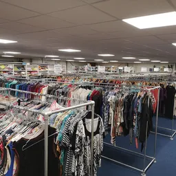 Rekken met tweedehands kleding in diverse kleuren en stijlen