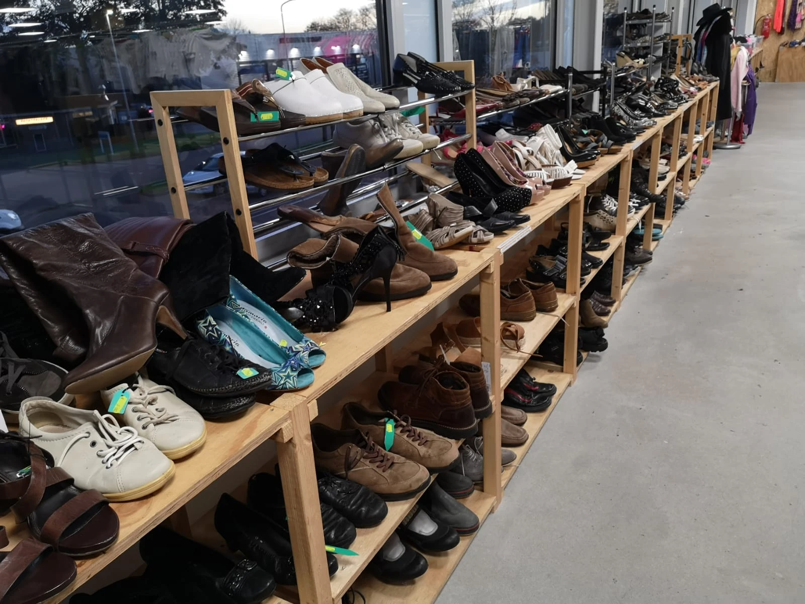 Houten stellingen vol met tweedehands schoenen en voetkleding in de kringloopwinkel