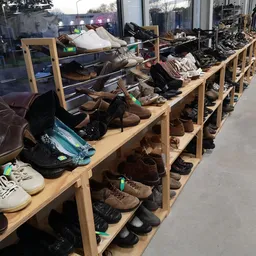 Houten stellingen vol met tweedehands schoenen en voetkleding in de kringloopwinkel