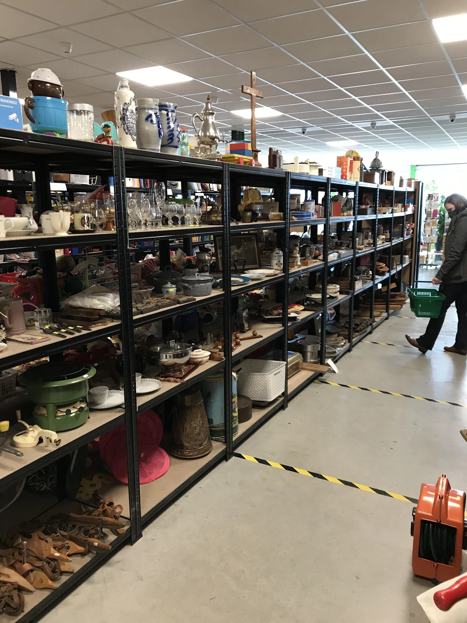 Zwarte stellingen vol met huishoudelijke artikelen, servies en diverse spullen in een kringloopwinkel