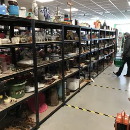 Zwarte stellingen vol met huishoudelijke artikelen, servies en diverse spullen in een kringloopwinkel