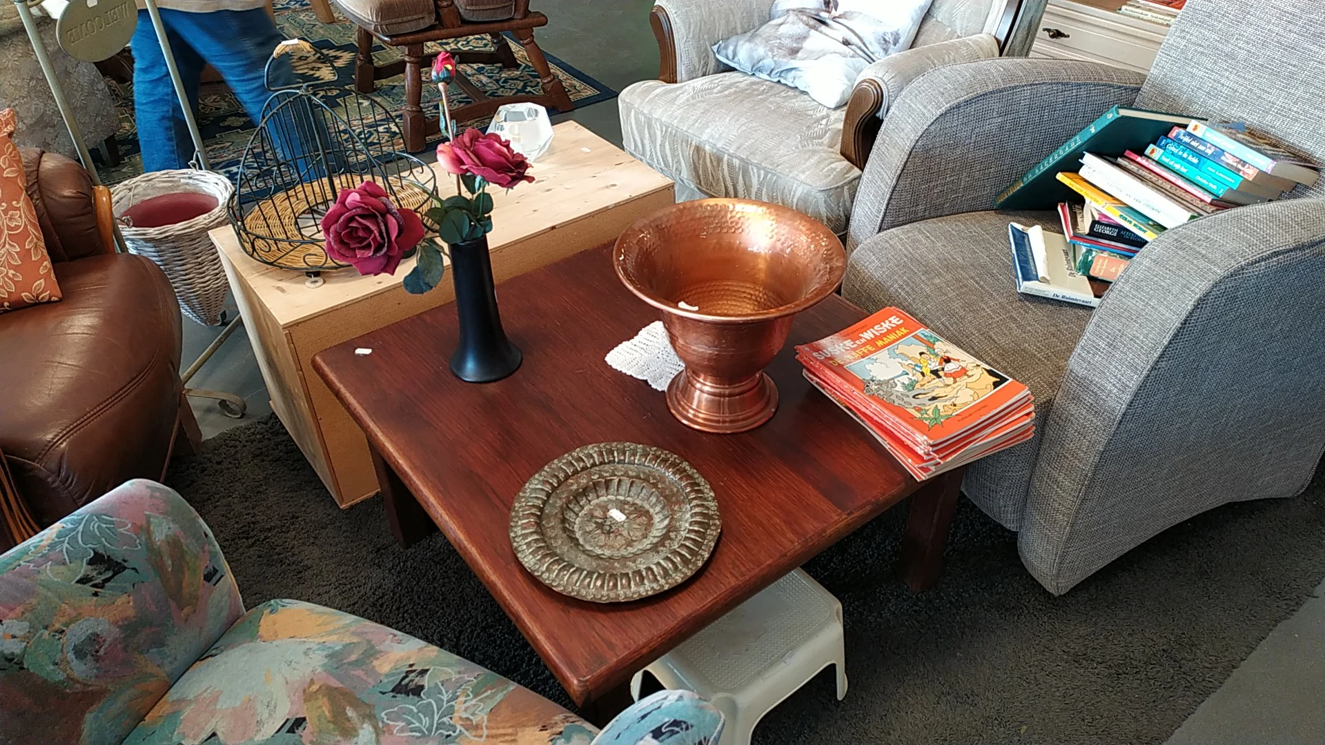 Houten salontafel met decoratieve koperen schaal, bloemenvaas en stapel boeken