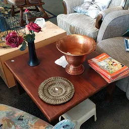 Houten salontafel met decoratieve koperen schaal, bloemenvaas en stapel boeken