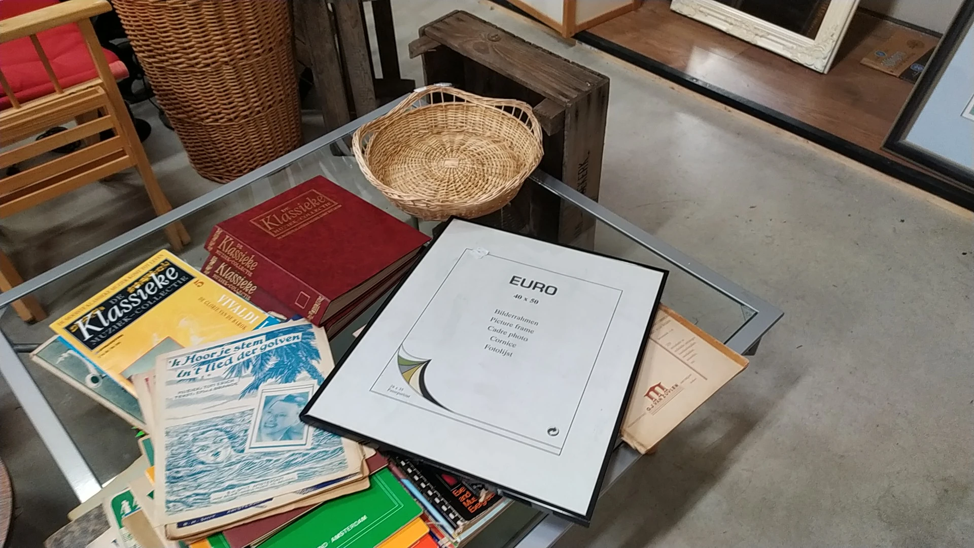 Tafel met tweedehands boeken, een geweven mand en een EURO-publicatie tussen andere spullen