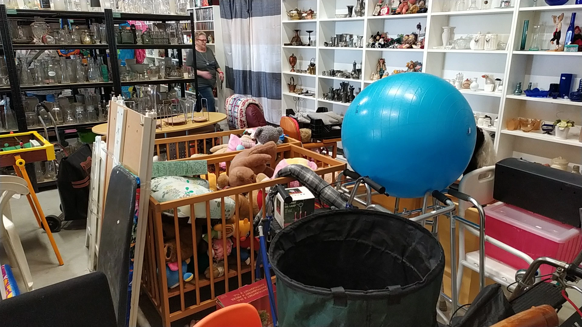 Kinderspeelhoek met wiegje, speelgoed en blauwe bal in een kringloopwinkel
