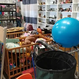 Kinderspeelhoek met wiegje, speelgoed en blauwe bal in een kringloopwinkel