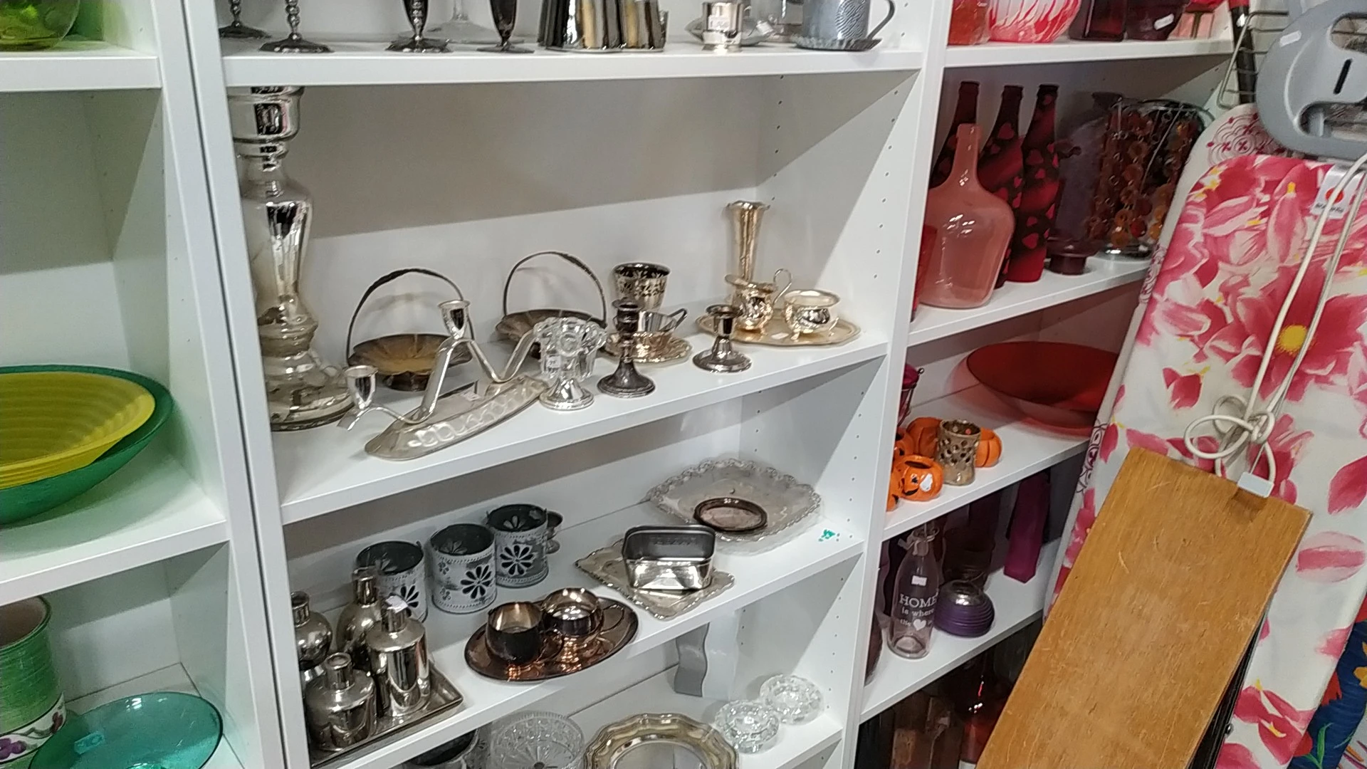 Witte stellingkast met zilverkleurig serviesgoed, kandelaars, vazen en decoratieve items op meerdere niveaus