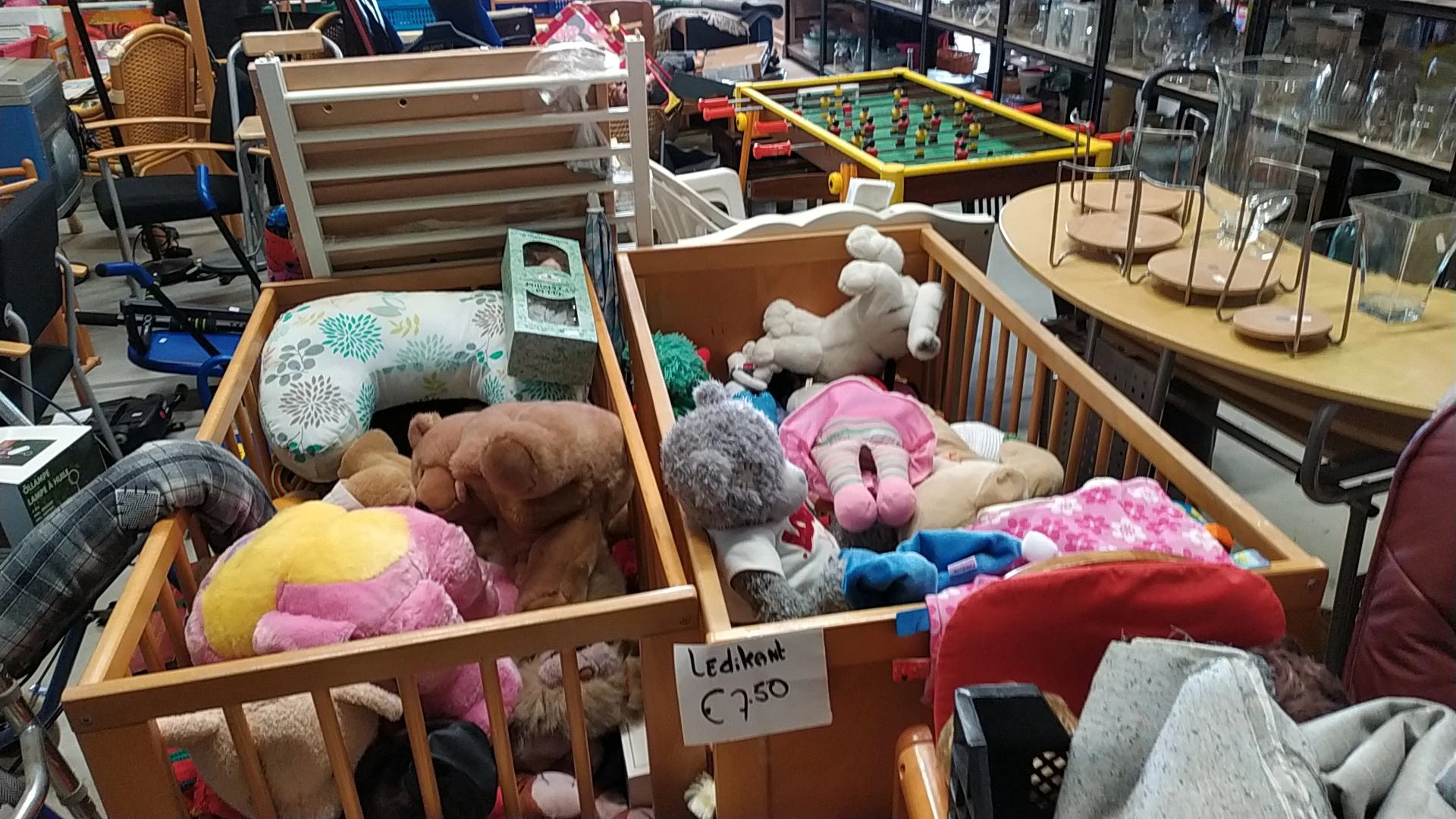 Houten boxen met knuffels, speelgoed en huishoudtextiel zoals kussens en dekens in de kringloopwinkel