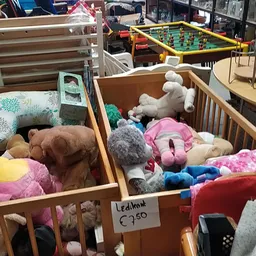 Houten boxen met knuffels, speelgoed en huishoudtextiel zoals kussens en dekens in de kringloopwinkel
