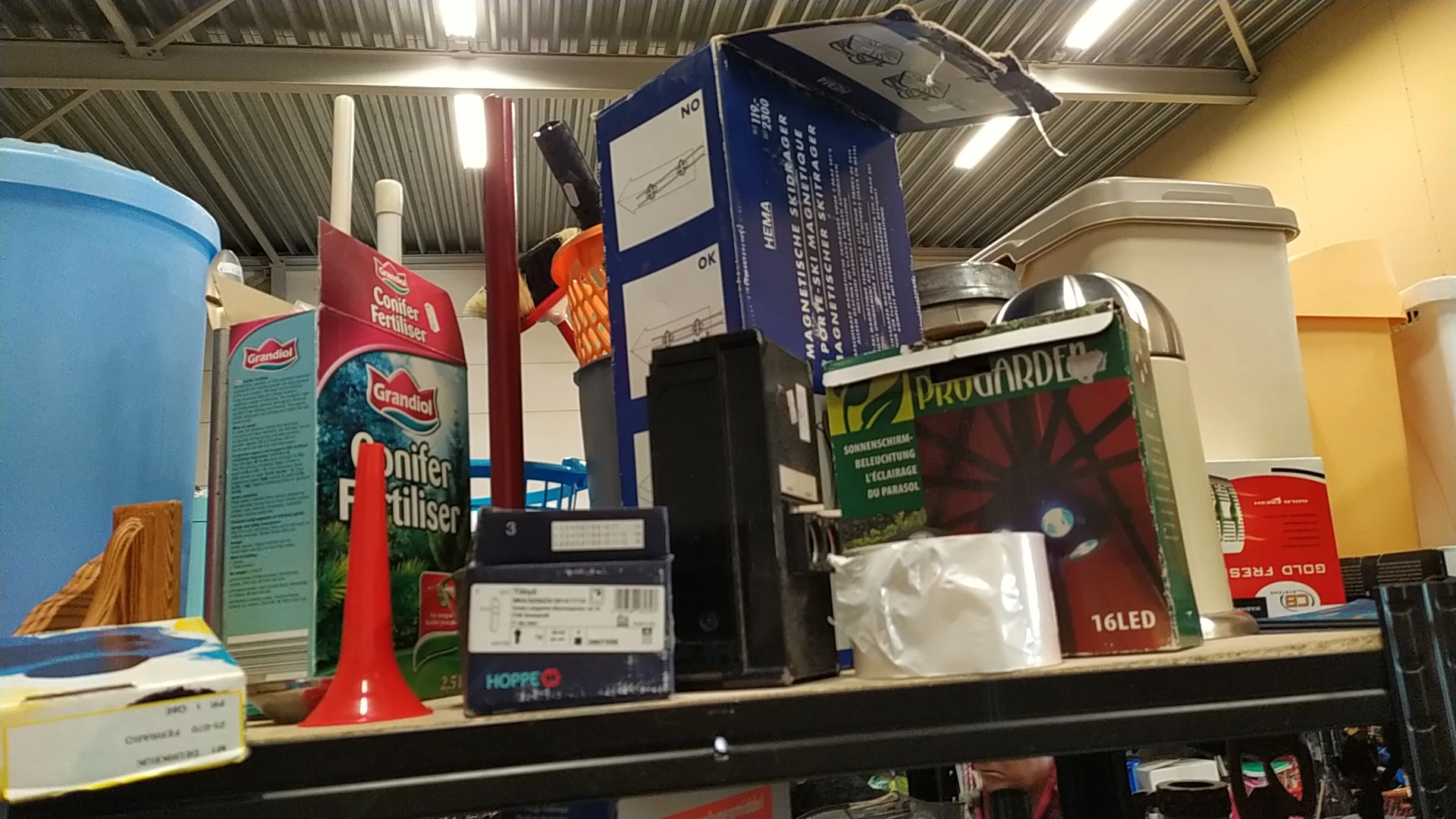 Stellage met diverse gebruikte artikelen zoals dozen, elektronica en huishoudspullen