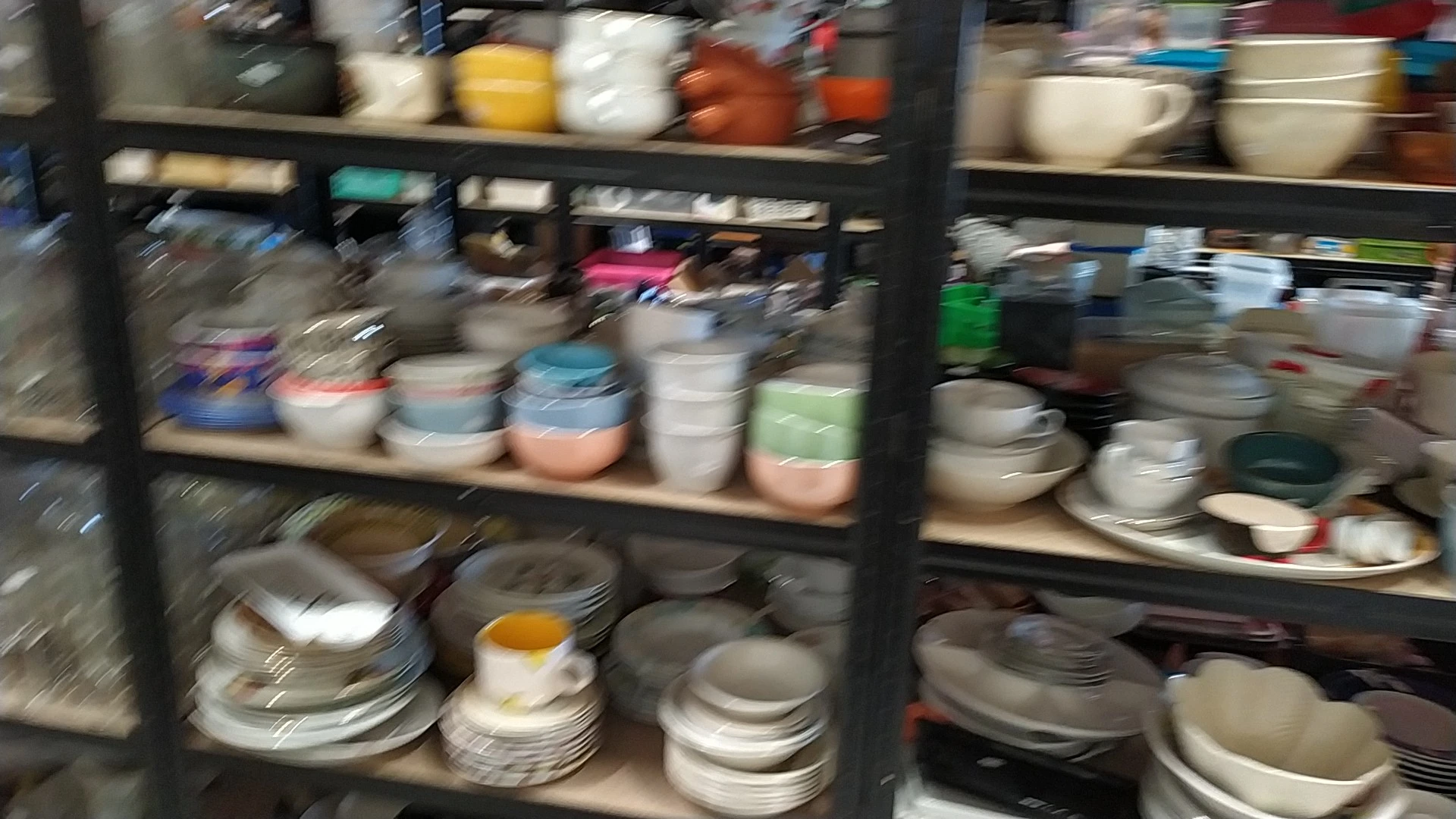 Stellingen met diverse serviesgoed, borden, schalen en bakjes in verschillende kleuren en maten