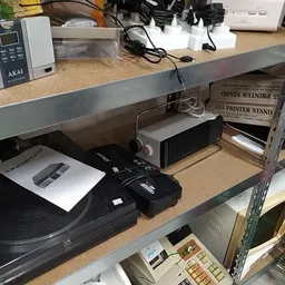 Tweedehands elektronica op een tafel, waaronder een platenspeler, versterker en ander audiotuig