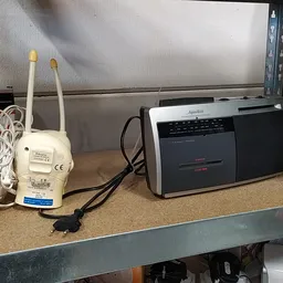 Tweedehands elektronica op een werkblad: wifi-router, cassettespeler en andere elektronische apparaten