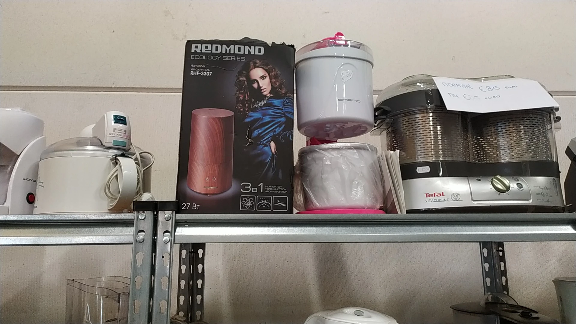 Rekken met diverse huishoudelijke artikelen waaronder een REDMOND-ketel en Tefal-apparaten