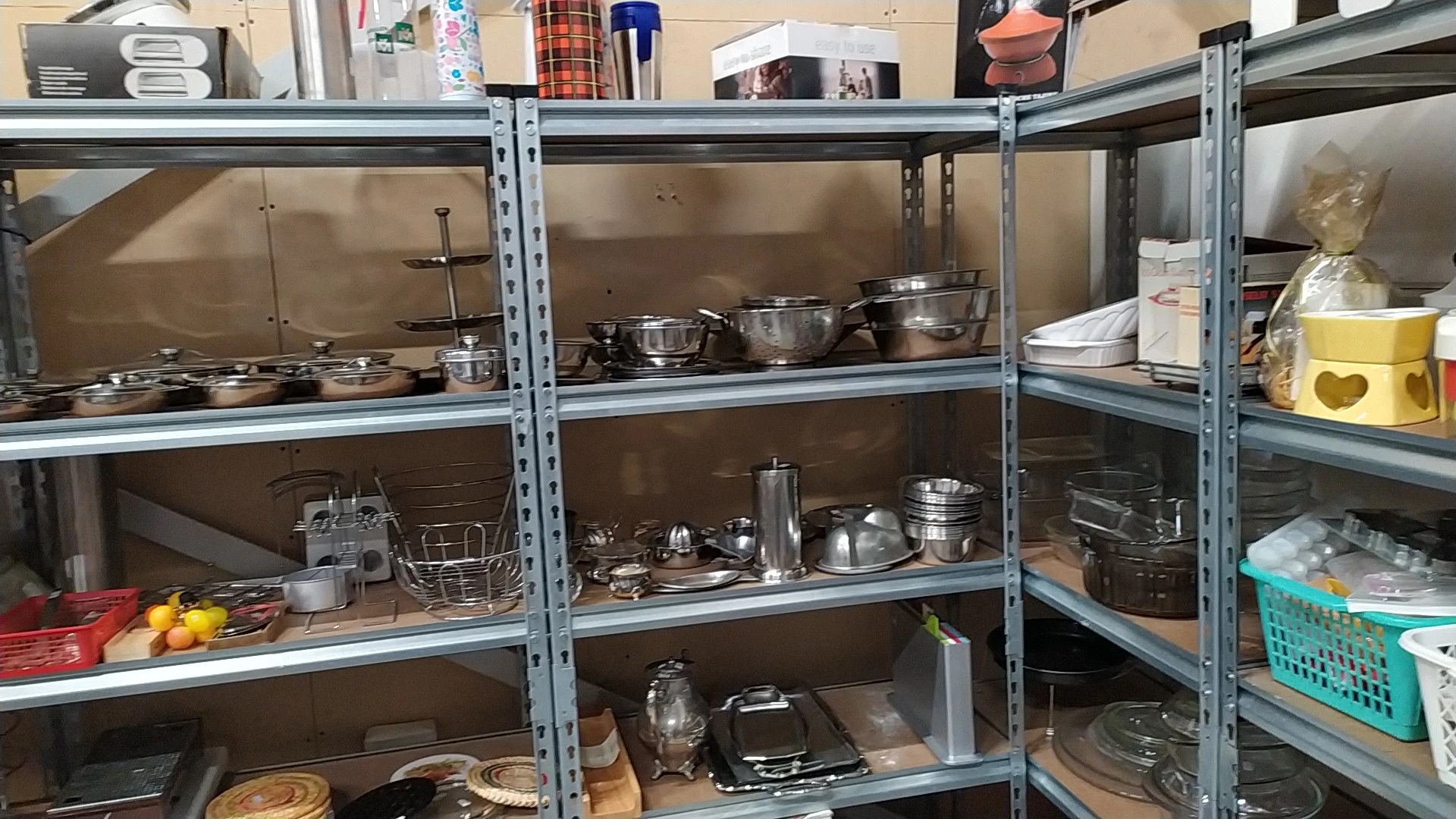 Metalen stellingen gevuld met kookgerei, pannen, schalen en keukengerei