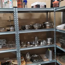 Metalen stellingen gevuld met kookgerei, pannen, schalen en keukengerei