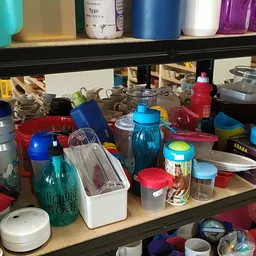 Verschillende huishoudelijke items en containers op een plank in een kringloopwinkel