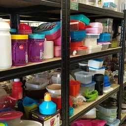 Stellingen met plastic bakken, doosjes en opbergcontainers in verschillende kleuren en maten