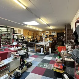 Winkelvloer met uiteenlopende tweedehands artikelen, tassen, kleding en huishoudspullen verspreid over verschillende tafels e
