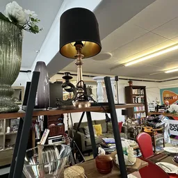 Winkelbinnenruimte met lampen, boeken, huishoudartikelen en decoratie op tafels en in kasten