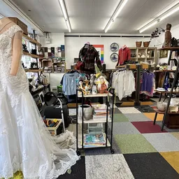 Winkelinterieur met kleding op rekken, mannequin met witte jurk, boeken en diverse spullen op stellingen