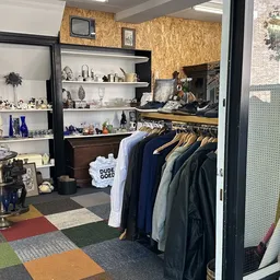 Winkelbinnenruimte met kledingrek, stellages met accessoires en decorstukken, kleurrijke tegelvloer