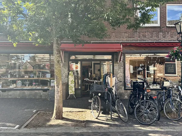 Winkelpui met rode luifel, fietsuitstalling ervoor, bakstenen gevel, winkelramen met etalage