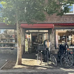 Winkelpui met rode luifel, fietsuitstalling ervoor, bakstenen gevel, winkelramen met etalage