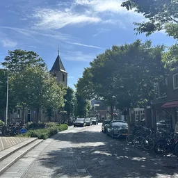 Dorpsstraat in Nootdorp met kerkgebouw en winkelpanden aan beide zijden