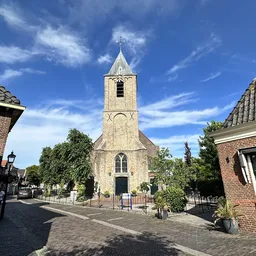 Kerkgebouw met toren in een dorpsstraat