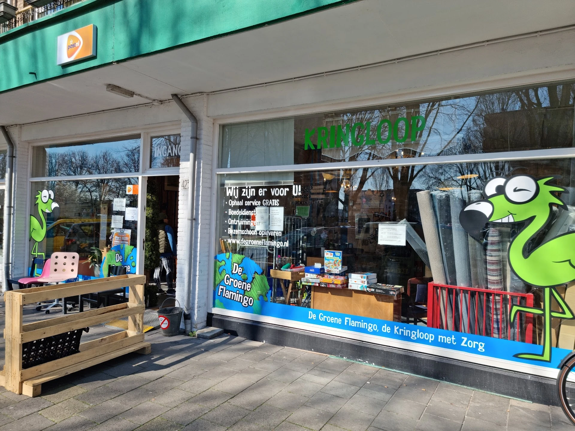 Gevel van Dude Goed Kringloop Winkel met groene decoratie en uitstalramen aan de voorkant